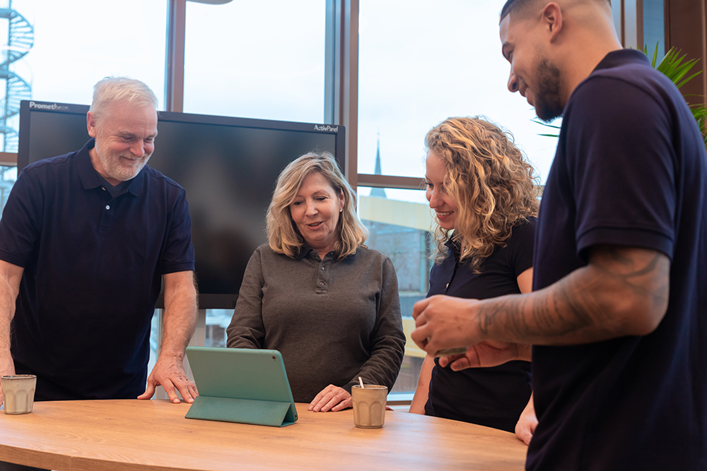 Leidinggevende en schoonmakers in overleg bij een iPad op een tafel