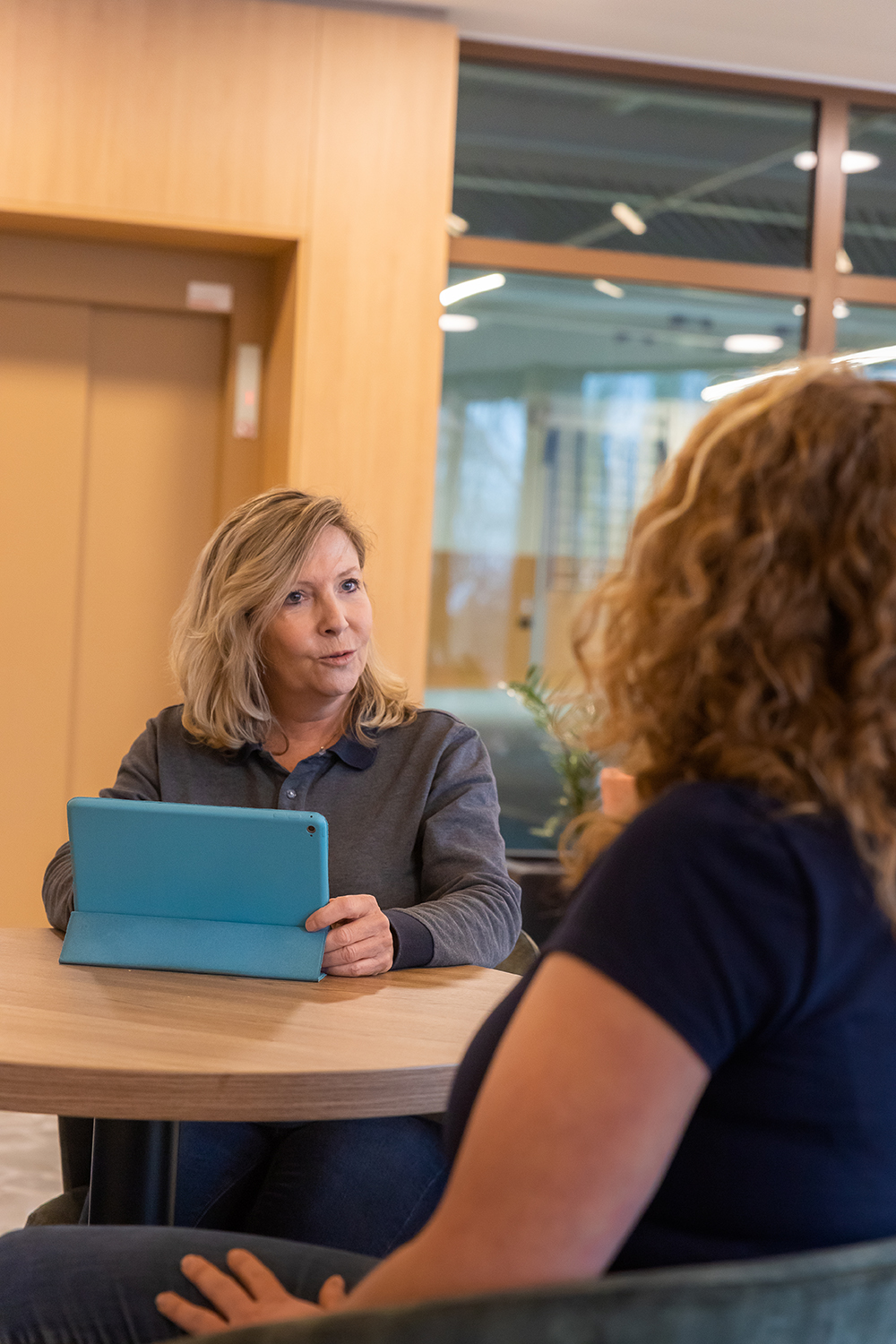Leidinggevende met ipad praat tegen schoonmaakmedewerker