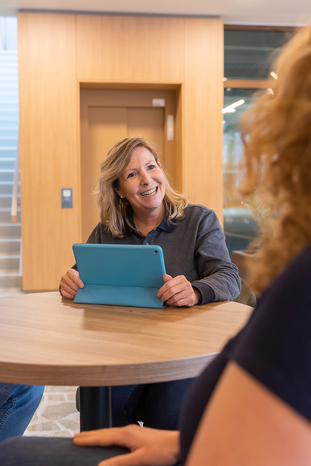 Leidinggevende zit lachend aan tafel met een iPad