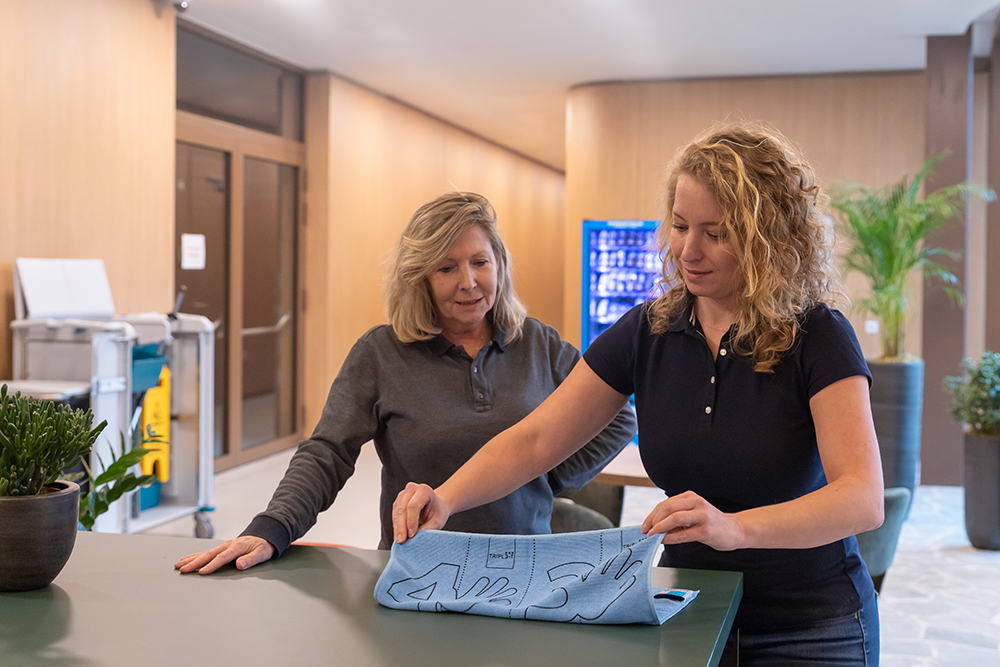 Leidinggevende en schoonmaker oefenen het correct vouwen van een microvezeldoek