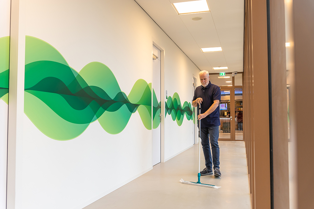 Schoonmaker stofwist een hal met groene graphic op de muur