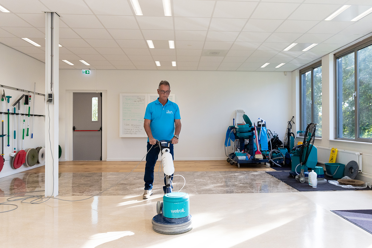 Schoonmaker bij IBN bezig met vloeronderhoud met een eenschijfsmachine
