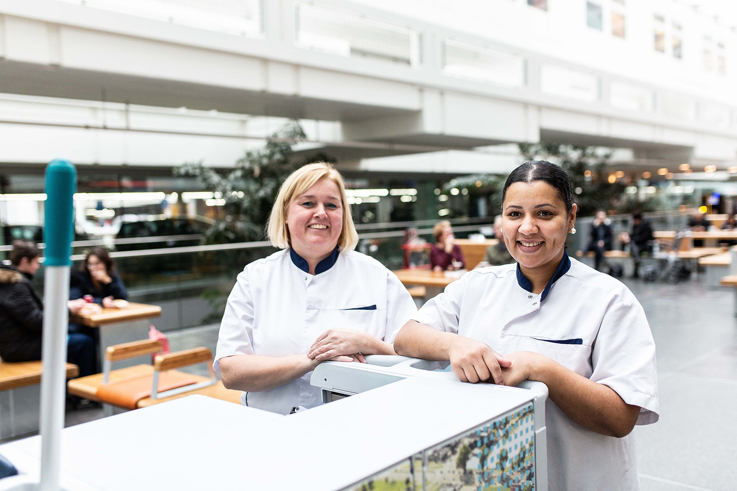 Twee vrolijke schoonmakers bij een Triple-T trolley
