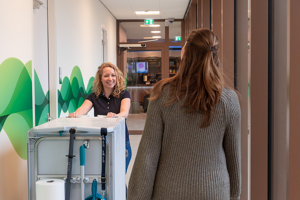 schoonmaker met trolley komt gebouwgebruiker tegen